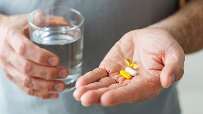 Пациент держит таблетки и стакан воды
